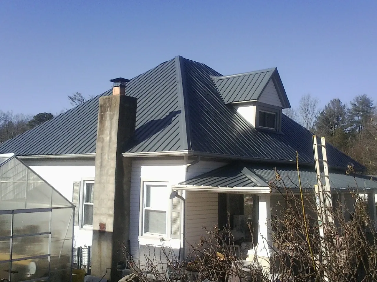 Dark blue standing seam metal roof on a white farmhouse with dormer — Slate & Tile Roof Repair by Roofing Brothers in Altadena